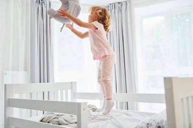 Yastıkla oynayıp fırlatıyorsun. Gündüz vakti evde rahat giyimli şirin küçük bir kız var..