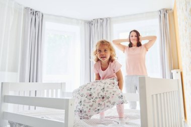 Genç bir anne ve küçük kızı evde birlikte günlük kıyafetler giyiyorlar..
