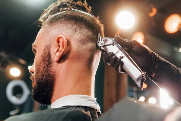 Berber dükkanında oturan ve saçını kestiren genç sakallı adama yakından bakın..