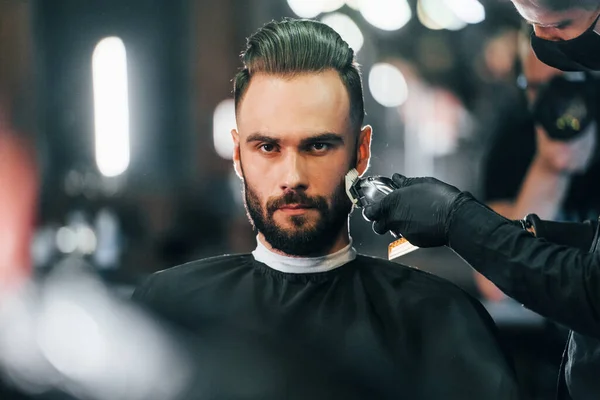 Jovem Com Penteado Elegante Sentado Recebendo Sua Barba Raspada Barbearia — Fotografia de Stock