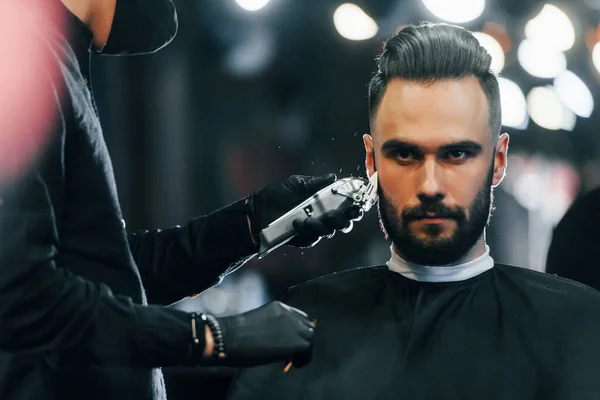 Jovem Com Penteado Elegante Sentado Recebendo Sua Barba Raspada Barbearia — Fotografia de Stock