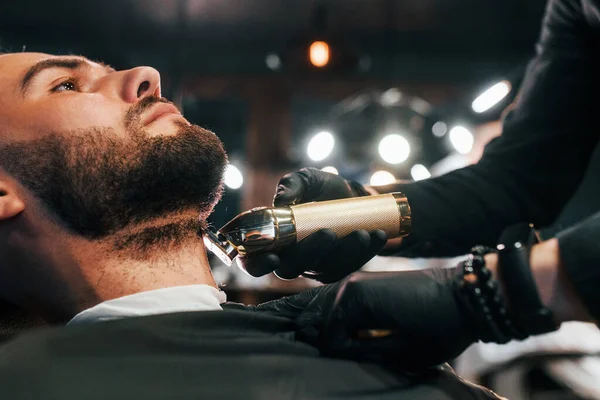 Jovem Com Penteado Elegante Sentado Recebendo Sua Barba Raspada Barbearia — Fotografia de Stock