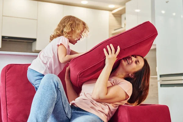 Eğleniyor ve zıplıyor. Genç bir anne ve küçük kızı evde birlikte günlük kıyafetler giyiyorlar..