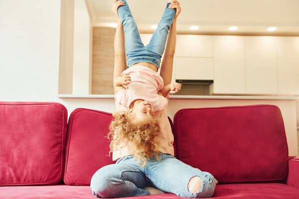 Young mother with her little daughter in casual clothes together indoors at home.