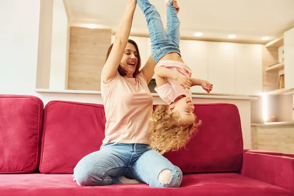 Genç bir anne ve küçük kızı evde birlikte günlük kıyafetler giyiyorlar..