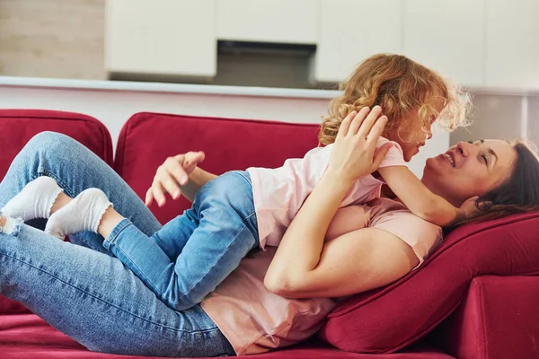 Kırmızı kanepede uzanıyordum. Genç bir anne ve küçük kızı evde birlikte günlük kıyafetler giyiyorlar..