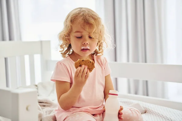 Sentada Cama Comiendo Galletas Bebiendo Leche Linda Niña Ropa Casual —  Fotos de Stock