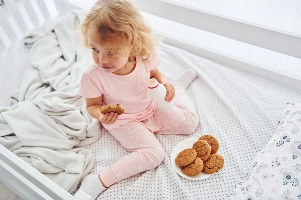 Kurabiye yiyerek kahvaltı yapmak. Gündüz vakti evde rahat giyimli şirin küçük bir kız var..