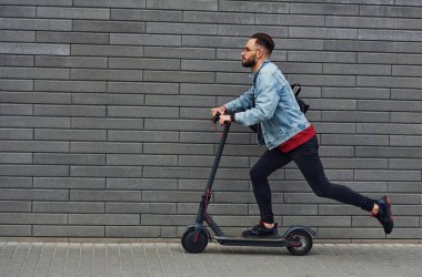 Güneşli bir günde dışarıda elektrikli sandalla gezen, günlük giysiler içinde yakışıklı bir gencin yan görüntüsü..