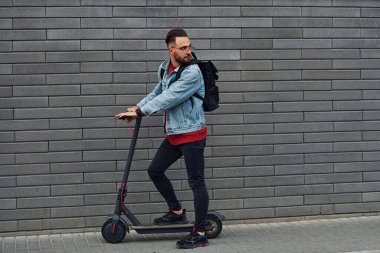 Güneşli bir günde dışarıda elektrikli sandalla gezen, günlük giysiler içinde yakışıklı bir gencin yan görüntüsü..