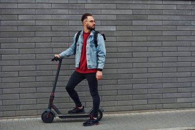 Güneşli bir günde dışarıda elektrikli sandalla gezen, günlük giysiler içinde yakışıklı bir gencin yan görüntüsü..