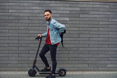 Güneşli bir günde dışarıda elektrikli sandalla gezen, günlük giysiler içinde yakışıklı bir gencin yan görüntüsü..