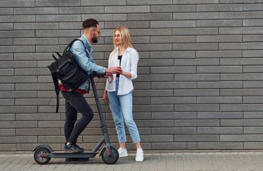 Elektrikli ayakkabıyla. Açık havada bir kadınla birlikte şık bir genç adam. Arkadaşlık ya da ilişki kavramı.