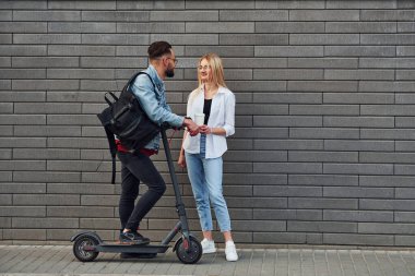 Elektrikli ayakkabıyla. Açık havada bir kadınla birlikte şık bir genç adam. Arkadaşlık ya da ilişki kavramı.