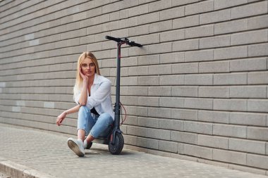 Gündüz vakti açık havada elektrikli sandalyede oturan günlük kıyafetli güzel bir sarışın..