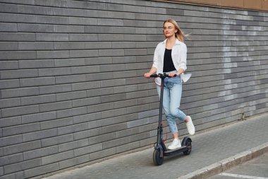 Gündüz vakti açık havada elektrikli sandalla gezen günlük kıyafetli güzel bir sarışın..