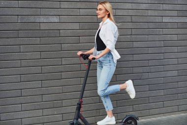 Gündüz vakti açık havada elektrikli sandalla gezen günlük kıyafetli güzel bir sarışın..