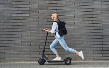 Güneşli bir günde açık havada elektrikli sandalla gezen günlük kıyafetlerle güzel sarışının yan görüntüsü..