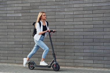 Güneşli bir günde açık havada elektrikli sandalla gezen günlük kıyafetlerle güzel sarışının yan görüntüsü..