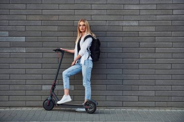 Güneşli bir günde açık havada elektrikli sandalla gezen günlük kıyafetlerle güzel sarışının yan görüntüsü..