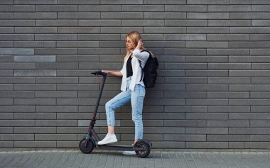 Güneşli bir günde açık havada elektrikli sandalla gezen günlük kıyafetlerle güzel sarışının yan görüntüsü..