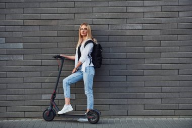 Güneşli bir günde açık havada elektrikli sandalla gezen günlük kıyafetlerle güzel sarışının yan görüntüsü..