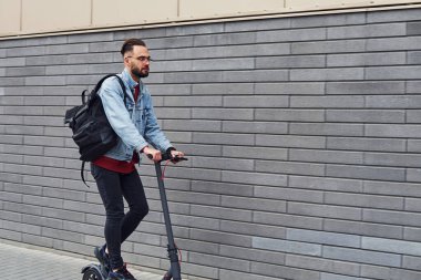 Güneşli bir günde dışarıda elektrikli sandalla gezen, günlük giysiler içinde yakışıklı bir gencin yan görüntüsü..