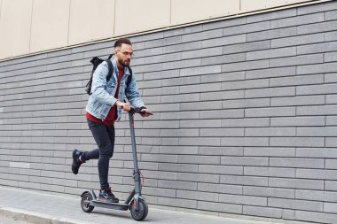 Gündüz vakti açık havada elektrikli sandalla gezen sıradan giysili yakışıklı bir genç..