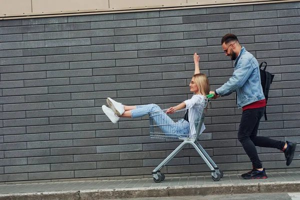 Plezier Hebben Winkelwagentje Rijden Jonge Stijlvolle Man Met Vrouw Casual — Stockfoto