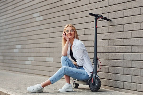 Gündüz vakti açık havada elektrikli sandalyede oturan günlük kıyafetli güzel bir sarışın..