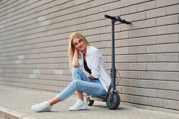 Gündüz vakti açık havada elektrikli sandalyede oturan günlük kıyafetli güzel bir sarışın..