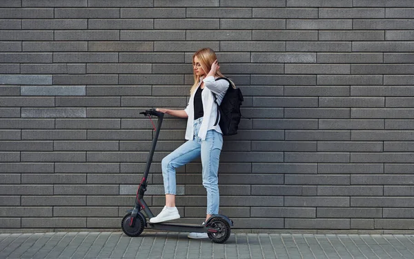 Güneşli bir günde açık havada elektrikli sandalla gezen günlük kıyafetlerle güzel sarışının yan görüntüsü..