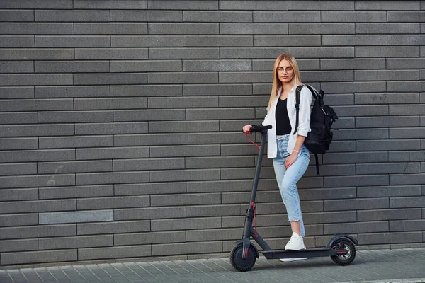 Güneşli bir günde açık havada elektrikli sandalla gezen günlük kıyafetlerle güzel sarışının yan görüntüsü..