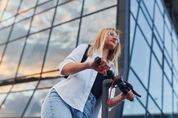 Modern Business Building Beautiful Blonde Casual Clothes Riding Electric Schooter —  Fotos de Stock