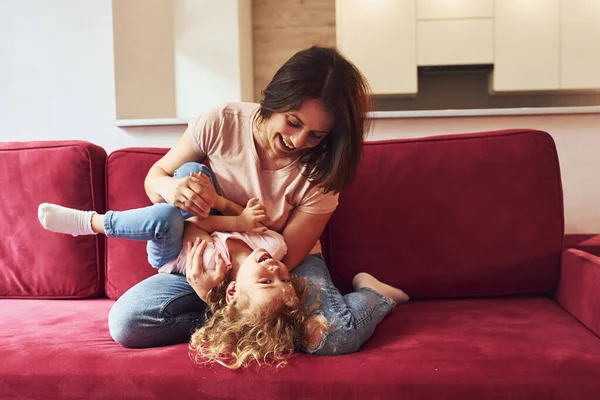 Kırmızı kanepede uzanıyordum. Genç bir anne ve küçük kızı evde birlikte günlük kıyafetler giyiyorlar..