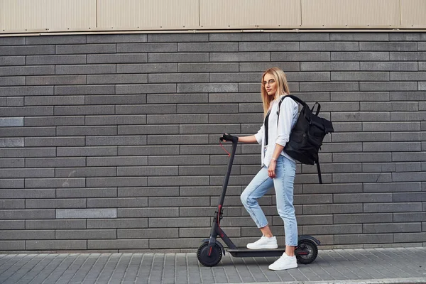 Grey Wall Beautiful Blonde Casual Clothes Riding Electric Schooter Outdoors — Stockfoto