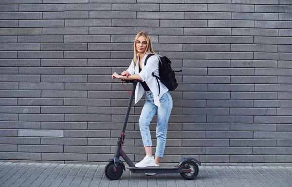 Grey Wall Beautiful Blonde Casual Clothes Riding Electric Schooter Outdoors — 스톡 사진