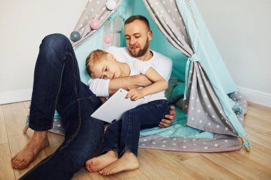 Baba ve yavruları çadırın yanında oturup birlikte vakit geçiriyorlar..