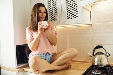 Mutfakta. Genç bayan dinleniyor ve hafta sonunu evde yalnız geçiriyor..