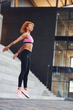 Avrupalı genç, kızıl saçlı, açık havada spor elbiseli bir kadın..