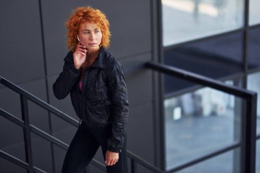 Açık havada duran Avrupalı genç, kızıl saçlı, spor elbiseli bir kadın..