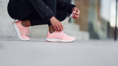 Dışarıda oturan ve ayakkabı giyen kadının yakın görüntüsü..
