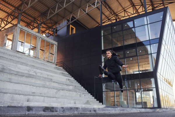 Doing crazy tricks. Young brunette in sportive clothes have fitness day outdoors in the city.