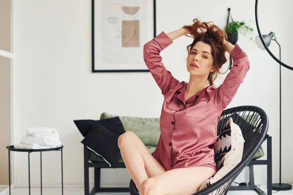 Pembe pijamalı seksi genç kadın gündüz vakti sandalyede oturuyor..