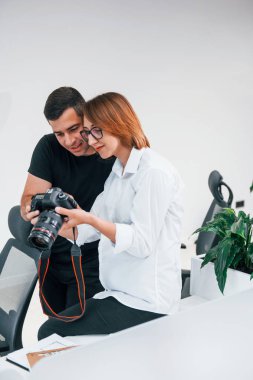 Siyah elbiseli bir adam, kadının fotoğrafçı kamerasından fotoğraf izliyor..