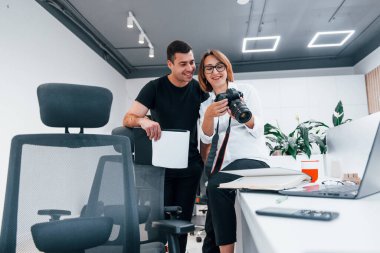 Siyah elbiseli bir adam, kadının fotoğrafçı kamerasından fotoğraf izliyor..