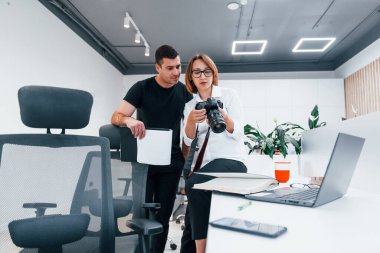 Siyah elbiseli bir adam, kadının fotoğrafçı kamerasından fotoğraf izliyor..