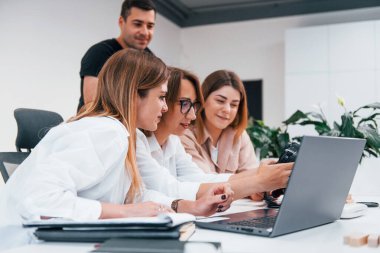 Ofiste çalışan bir grup resmi giyinmiş iş adamının önünde..