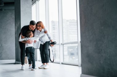 Resmi giyinmiş bir kadın ve elinde kamerayla boş bir odada koşan ve eğlenen bir adamla..