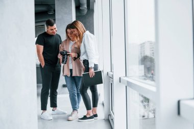Bir grup insan içeride birlikte durup kameradaki fotoğraflara bakıyorlar..